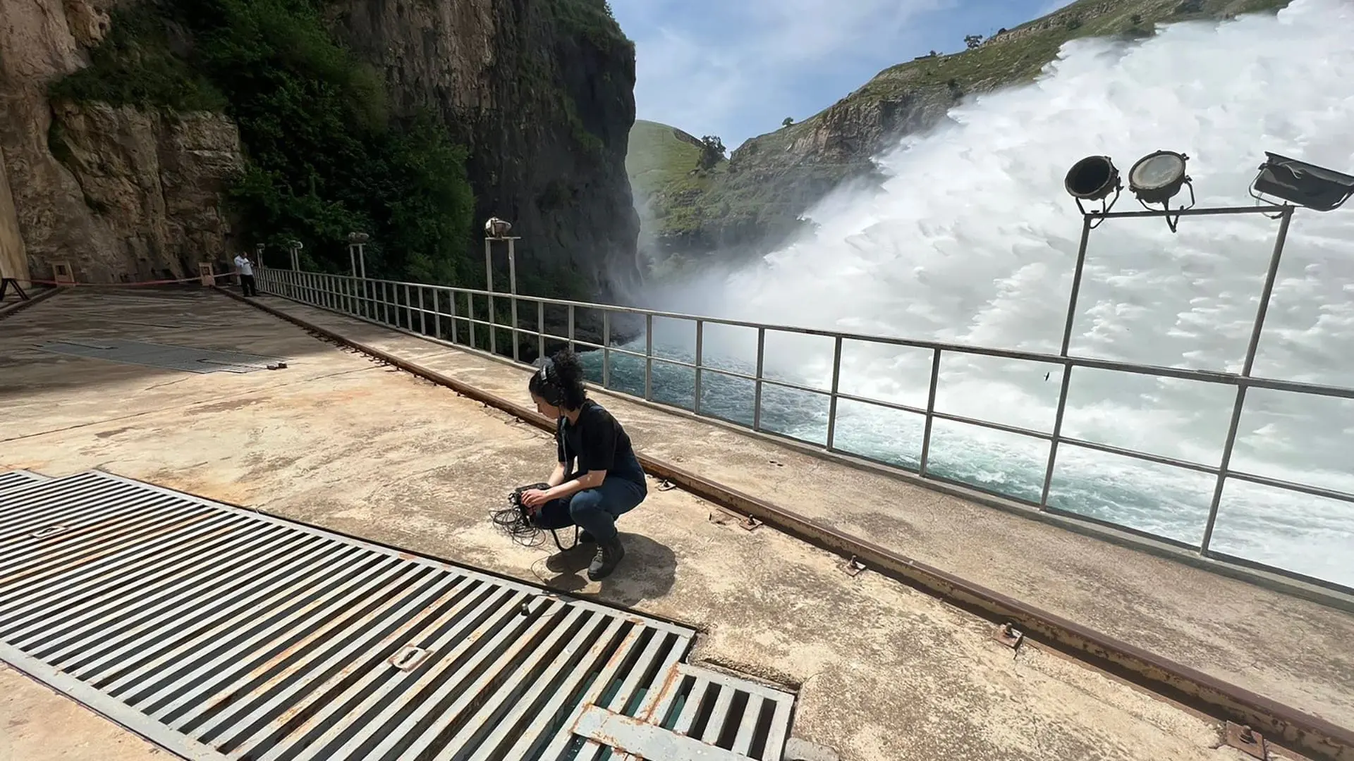 Su outdoors with headphones near dam