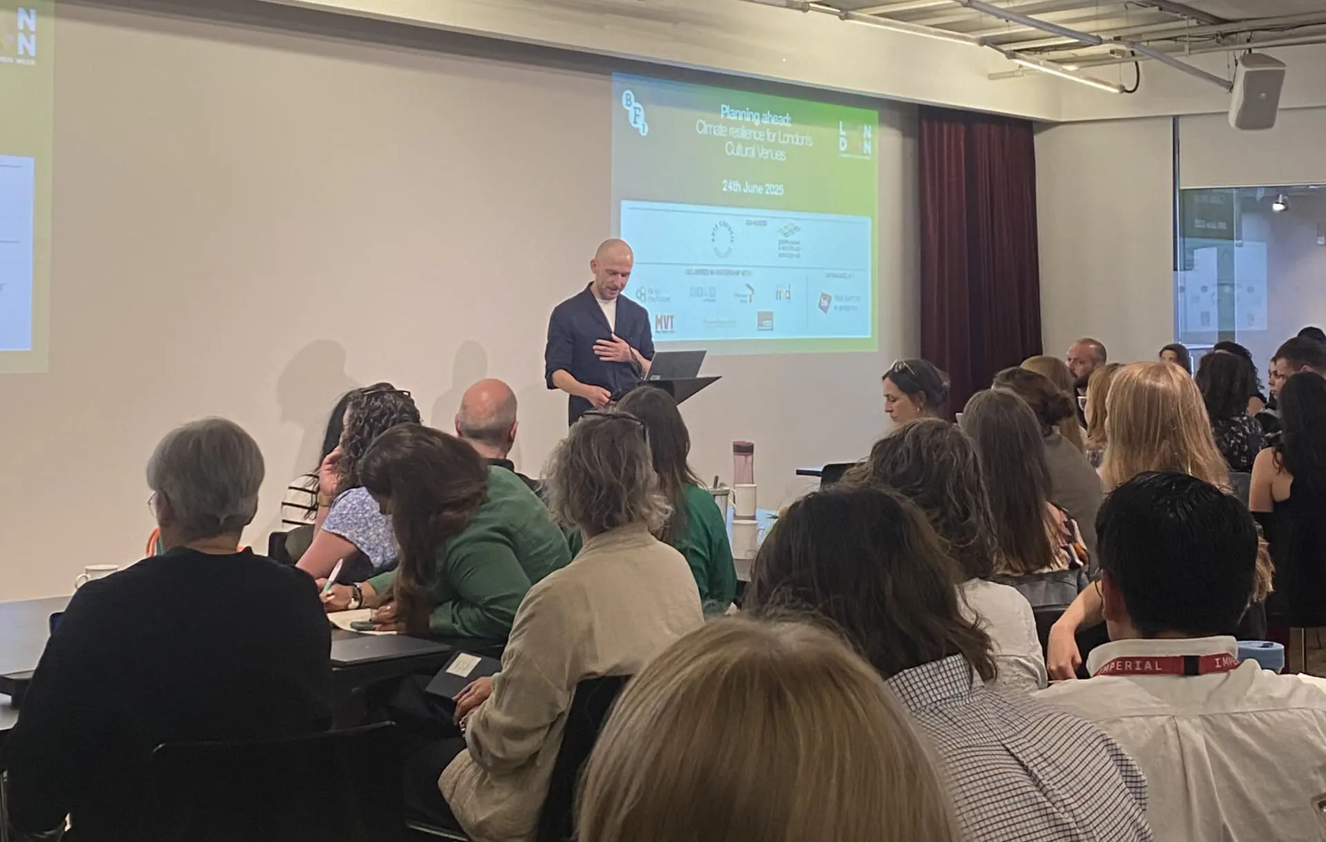 A group of people in a room watching a man give a presentation