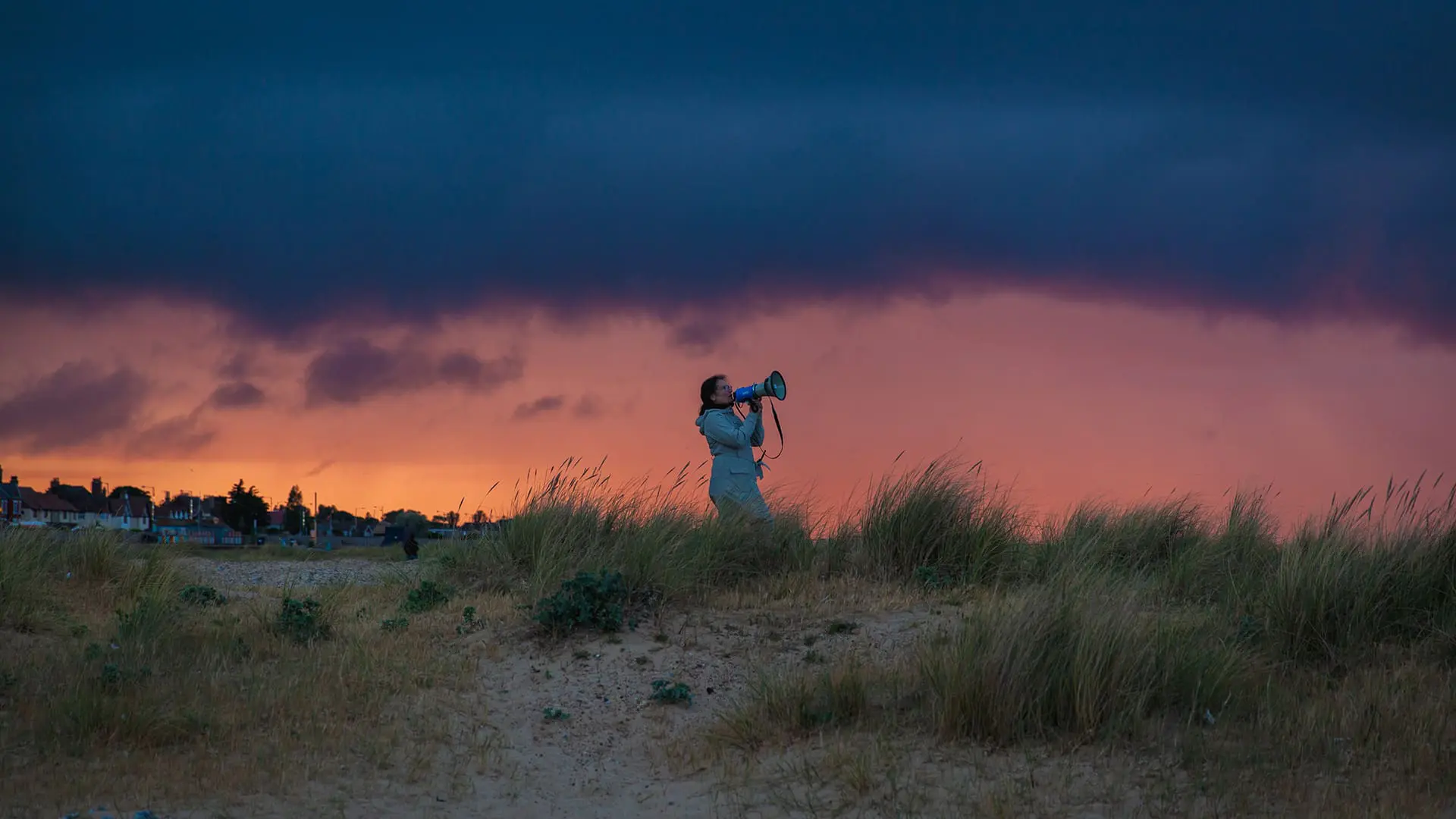 Person with megaphone during dawn or dusk on sandy dunes