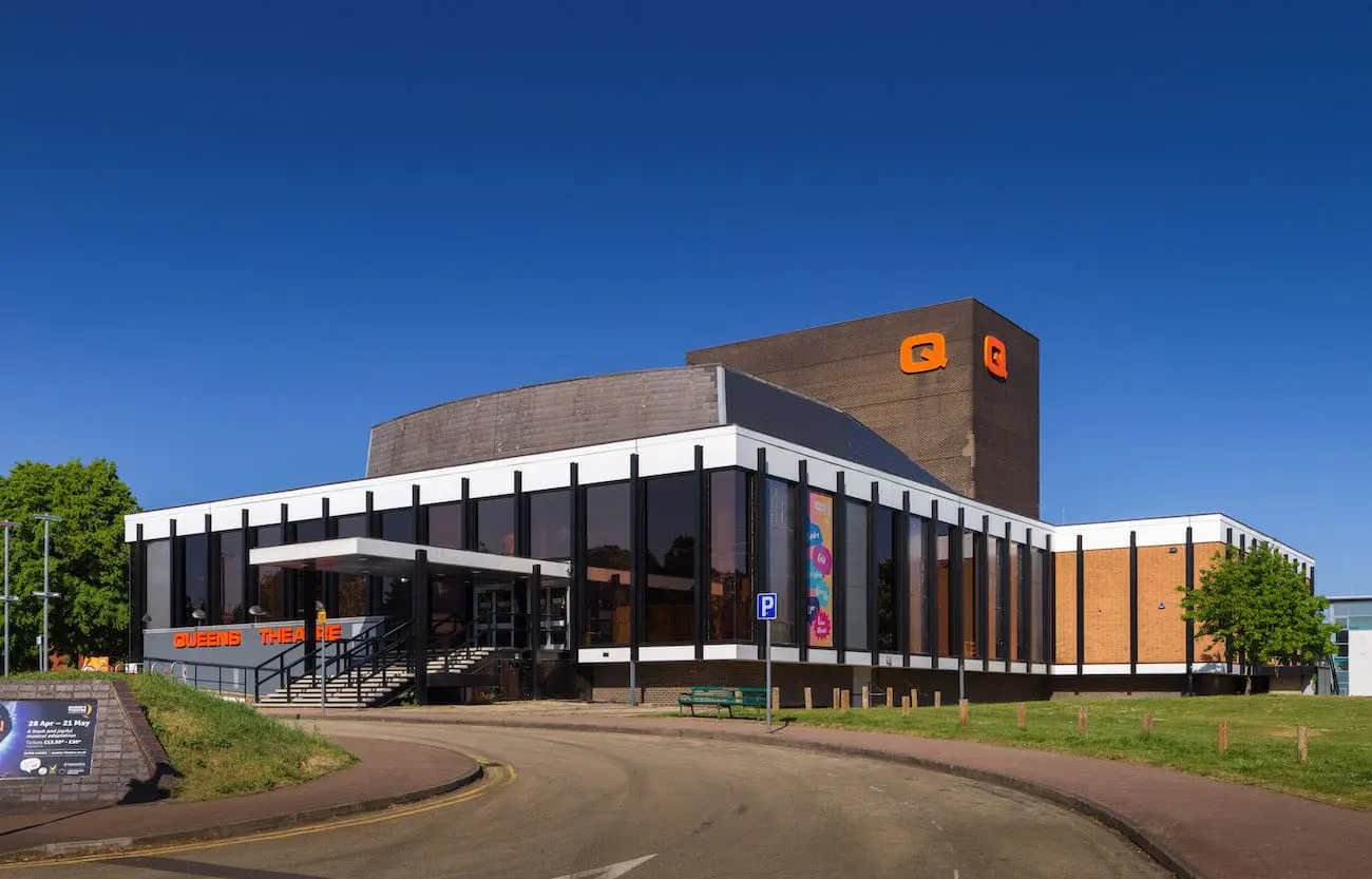 Building with glass windows and red brick exterior against a blue sky