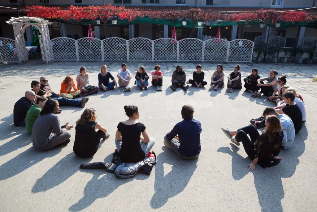 creative climate leaders sat in a circle on the floor facing one another, with long shadows