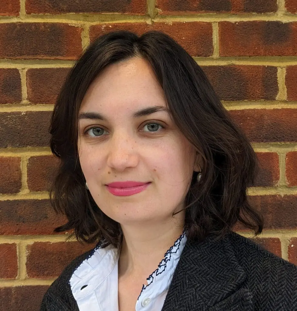 Karishma Rafferty headshot smiling with brick wall behind