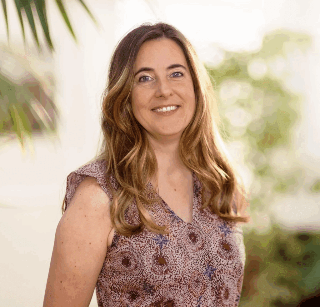 Catherine Bottrill headshot, smiling, outdoors, fern in the background but blurred out