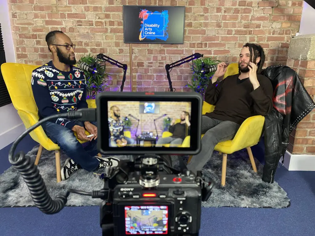 two people sat part of an interview and they are being filmed