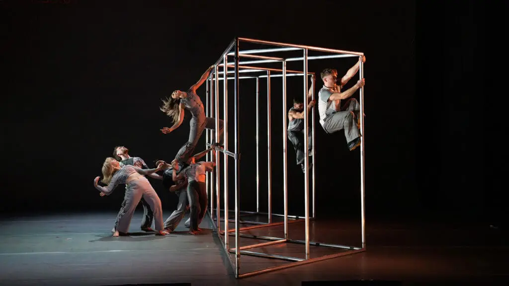 people dancing and scaling a square structure