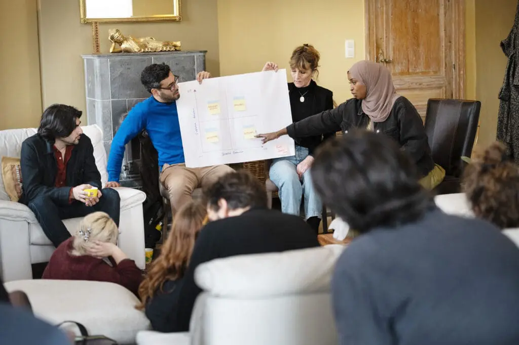 JB trainers facilitating an event pointing to a flipchart of vibrant notes