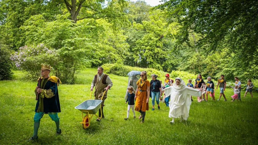 performers outdoors in green forest, colourful and vibrant scene