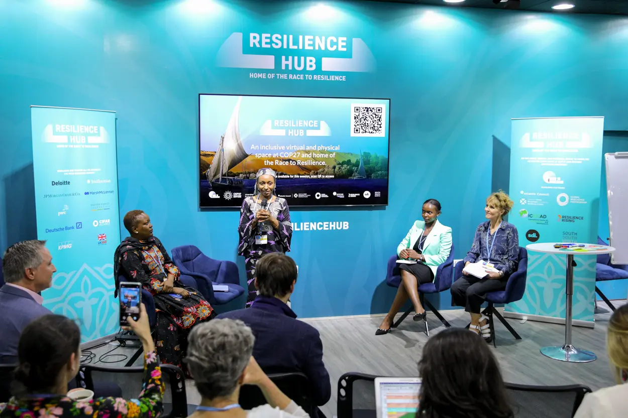 People doing talk at COP27 Resilience Hub, blue background and screen