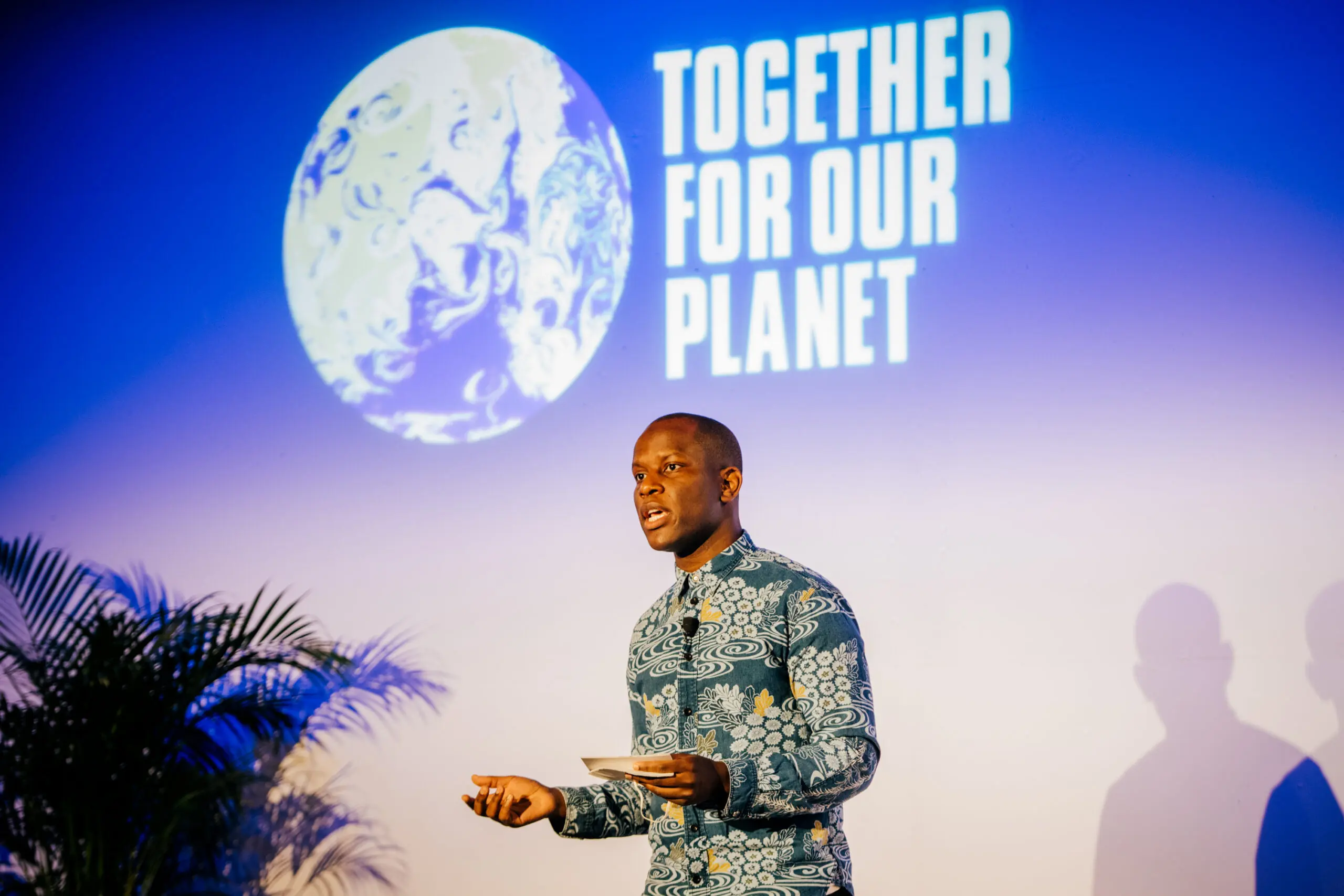 Love Ssega doing a talk with "Together for our Planet" text in the background