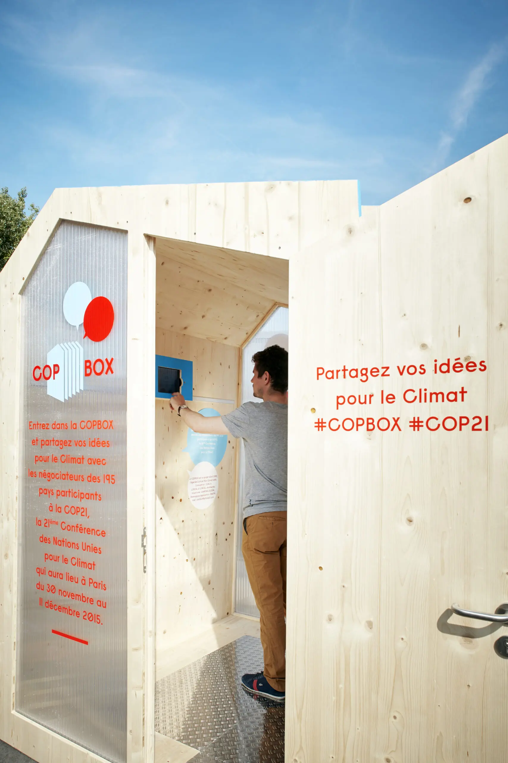 COP21 Box - person writing in a wooden box hut