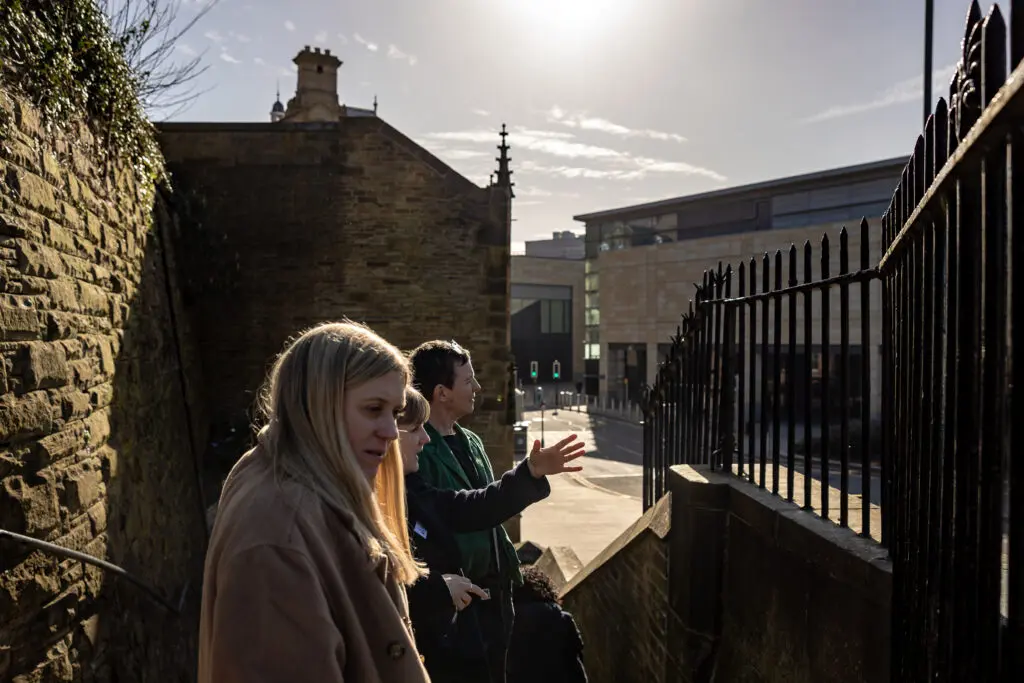 Three people standing on some steps in the sunshine in the city.