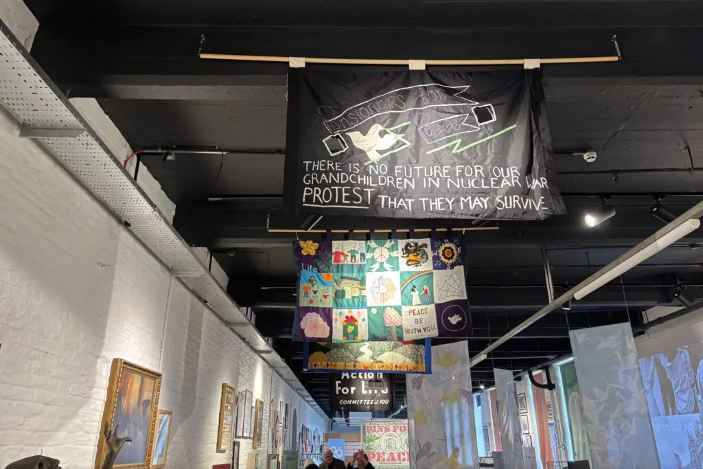 Inside Peace Museum, protest banners hang from the ceiling, the closest reads : There is no future for our grandchildren in nuclear war protest that they may survive"