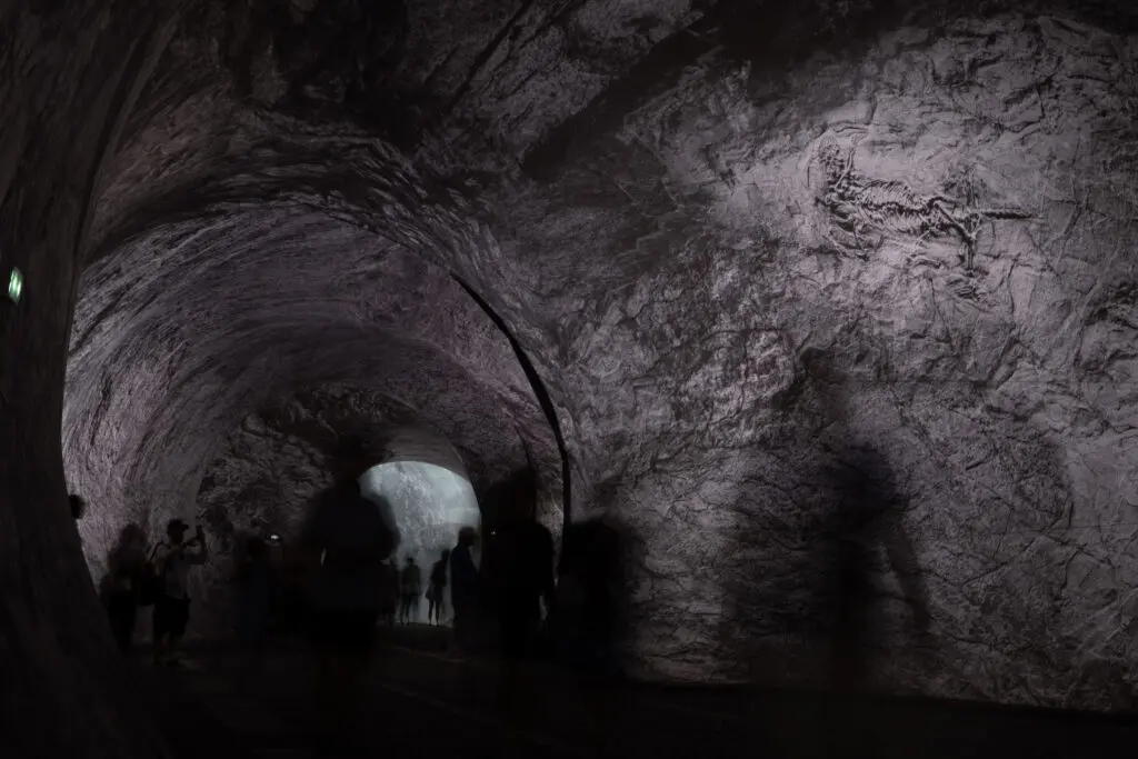 A darkened passageway with shadowy figrues moving through it
