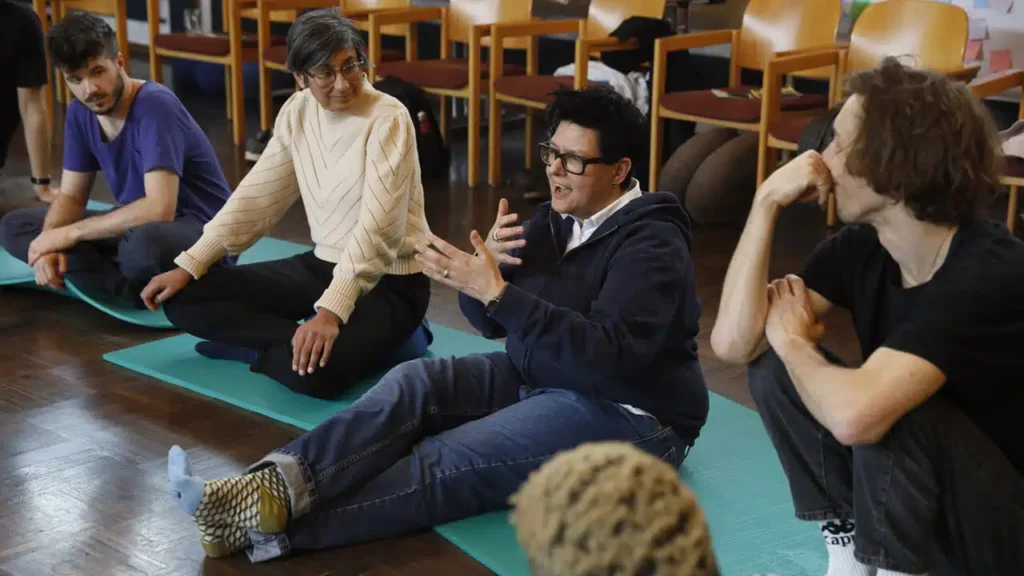 people sat on the floor, looking at one person talking
